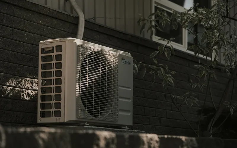 An air conditioning unit on the outside wall of a house